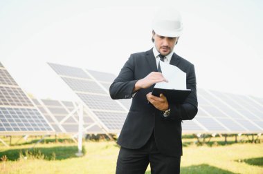 Solar power plant. Man standing near solar panels. Renewable energy.