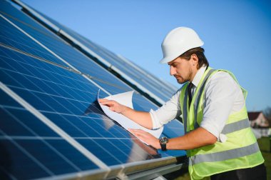 Güneş çiftliği, mühendis ile güneş paneli sistemin işleyişini kontrol eder, dünyanın enerjisini korumak için alternatif enerji, temiz enerji üretimi için fotovoltaik modül fikri.