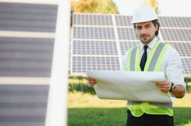 Güneş çiftliği, mühendis ile güneş paneli sistemin işleyişini kontrol eder, dünyanın enerjisini korumak için alternatif enerji, temiz enerji üretimi için fotovoltaik modül fikri.