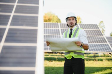 Güneş çiftliği, mühendis ile güneş paneli sistemin işleyişini kontrol eder, dünyanın enerjisini korumak için alternatif enerji, temiz enerji üretimi için fotovoltaik modül fikri.