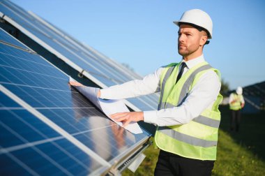 Güneş panellerinin yanında duran işadamı veya mühendis.