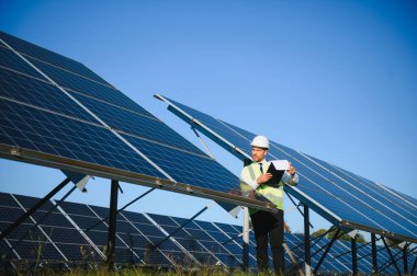 Güneş panellerinin yanında duran işadamı veya mühendis.