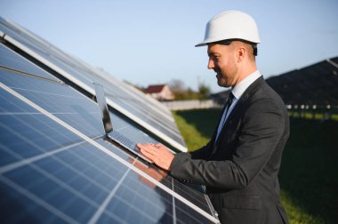 Güneş panellerinin yanında duran işadamı veya mühendis.