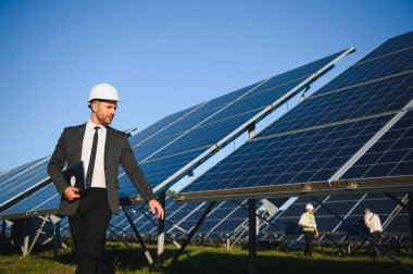 Solar power plant. Man standing near solar panels. Renewable energy.