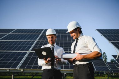 Güneş çiftliği, güneş paneli ve iki mühendis sistemin işleyişini kontrol etmek için yürür, dünyanın enerjisini korumak için alternatif enerji, temiz enerji üretimi için fotovoltaik modül fikri.