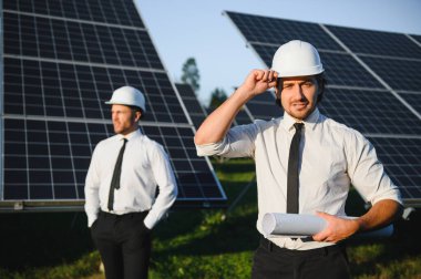 Güneş enerjisi bataryalarının yanındaki işadamı ve işçi.