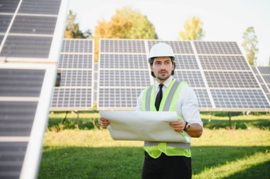Solar power plant. Man standing near solar panels. Renewable energy.