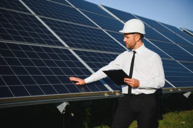 Güneş çiftliği, mühendis ile güneş paneli sistemin işleyişini kontrol eder, dünyanın enerjisini korumak için alternatif enerji, temiz enerji üretimi için fotovoltaik modül fikri.