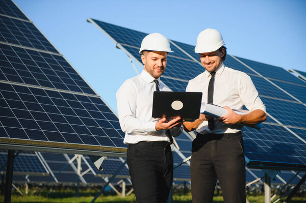 Солнечная панель фермы. Два европейских инженера осматривают солнечные панели. Рабочие на солнечной электростанции.