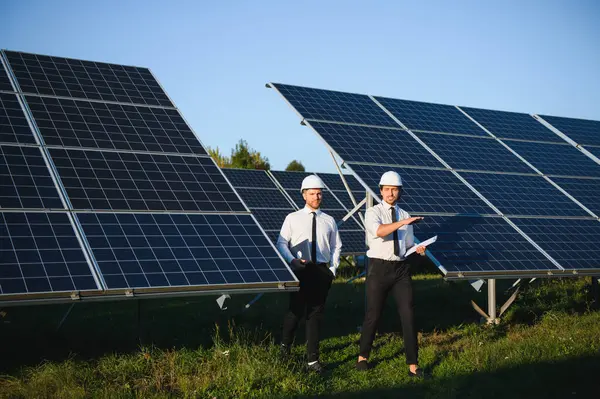 Güneş çiftliği, güneş paneli ve iki mühendis sistemin işleyişini kontrol etmek için yürür, dünyanın enerjisini korumak için alternatif enerji, temiz enerji üretimi için fotovoltaik modül fikri.