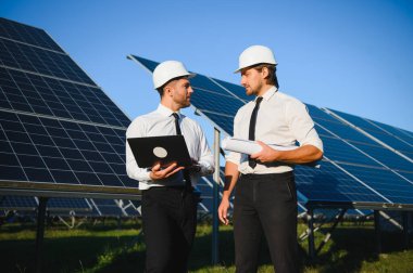 Portrait of engineers standing outside near solar panels. clipart