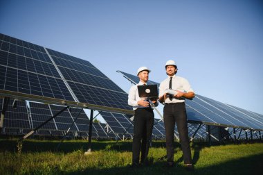 Portrait of engineers standing outside near solar panels. clipart