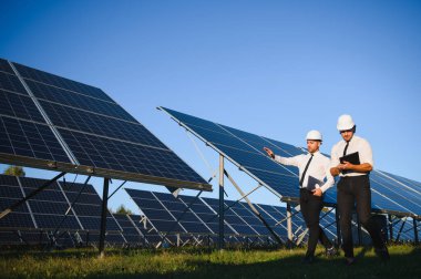 Güneş panellerinin yanında duran mühendislerin portresi.