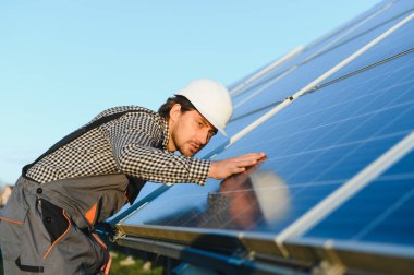Fotovoltaik güneş panelleri monte eden bir işçi. Miğfer mühendisi güneş modülü sistemi kuruyor. Alternatif, yenilenebilir enerji kavramı.