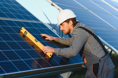 Güneşli bir günde güneş panelleri kuran güneş paneli teknisyeni.