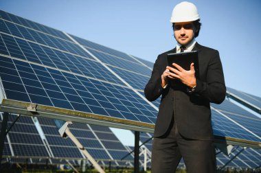 Güneş çiftliği, mühendis ile güneş paneli sistemin işleyişini kontrol eder, dünyanın enerjisini korumak için alternatif enerji, temiz enerji üretimi için fotovoltaik modül fikri.