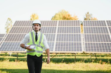 Başarılı bir işadamı ya da mühendis portresi güneş panellerini inceliyor. Yeşil enerji kavramı.