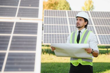 Güneş panellerinin yanında duran işadamı veya mühendis.