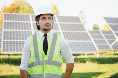 Solar power plant. Man standing near solar panels. Renewable energy.