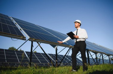Güneş panellerini inceleyen bir iş adamının portresi. Yeşil enerjiye yatırım kavramı.