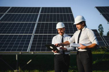 Güneş çiftliği, güneş paneli ve iki mühendis sistemin işleyişini kontrol etmek için yürür, dünyanın enerjisini korumak için alternatif enerji, temiz enerji üretimi için fotovoltaik modül fikri.