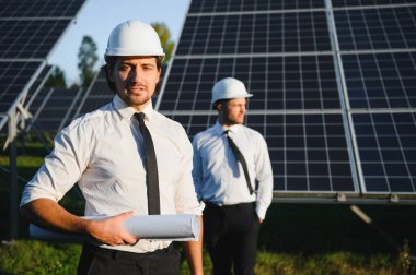 Güneş çiftliği, güneş paneli ve iki mühendis sistemin işleyişini kontrol etmek için yürür, dünyanın enerjisini korumak için alternatif enerji, temiz enerji üretimi için fotovoltaik modül fikri.