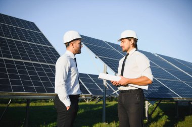 Güneş panellerinin yanında duran mühendislerin portresi.