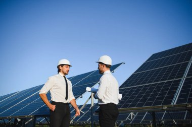 Güneş paneli çiftliği. İki Avrupalı mühendis güneş panellerini inceliyor. Güneş paneli çiftliğindeki işçiler.