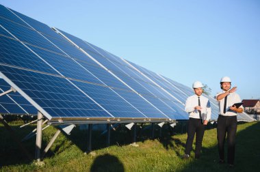 Güneş panellerinin yanında duran mühendislerin portresi.