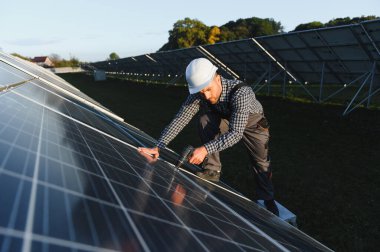 Fotovoltaik güneş panelleri monte eden bir işçi. Miğfer mühendisi güneş modülü sistemi kuruyor. Alternatif, yenilenebilir enerji kavramı.