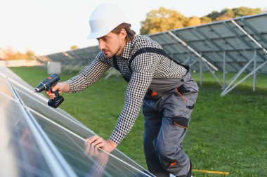 Fotovoltaik güneş panelleri monte eden bir işçi. Miğfer mühendisi güneş modülü sistemi kuruyor. Alternatif, yenilenebilir enerji kavramı.