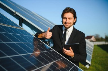 Güneş çiftliği, mühendis ile güneş paneli sistemin işleyişini kontrol eder, dünyanın enerjisini korumak için alternatif enerji, temiz enerji üretimi için fotovoltaik modül fikri.
