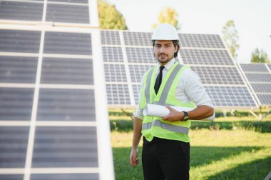 Solar power plant. Man standing near solar panels. Renewable energy.