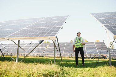 Solar power plant. Man standing near solar panels. Renewable energy.