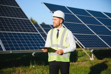 Güneş çiftliği, mühendis ile güneş paneli sistemin işleyişini kontrol eder, dünyanın enerjisini korumak için alternatif enerji, temiz enerji üretimi için fotovoltaik modül fikri.