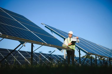 Güneş çiftliği, mühendis ile güneş paneli sistemin işleyişini kontrol eder, dünyanın enerjisini korumak için alternatif enerji, temiz enerji üretimi için fotovoltaik modül fikri.