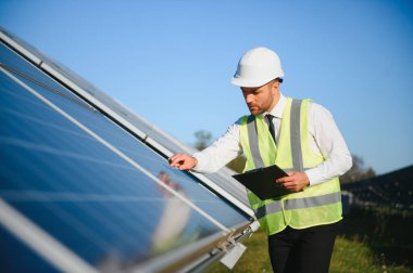 Güneş panellerinin yanında duran işadamı veya mühendis.