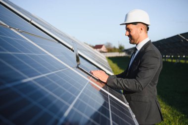 Solar power plant. Man standing near solar panels. Renewable energy.