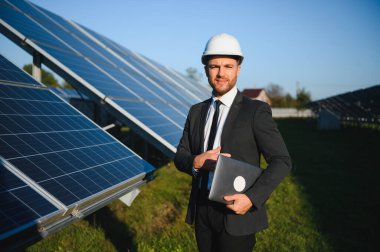 Güneş çiftliği, mühendis ile güneş paneli sistemin işleyişini kontrol eder, dünyanın enerjisini korumak için alternatif enerji, temiz enerji üretimi için fotovoltaik modül fikri.