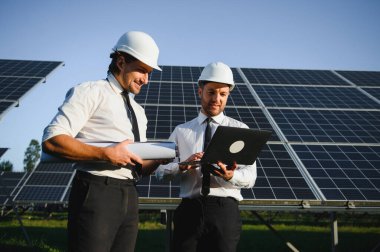 Güneş panellerinin yanında duran mühendislerin portresi.