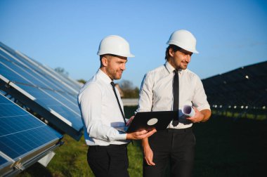 Güneş çiftliği, güneş paneli ve iki mühendis sistemin işleyişini kontrol etmek için yürür, dünyanın enerjisini korumak için alternatif enerji, temiz enerji üretimi için fotovoltaik modül fikri.