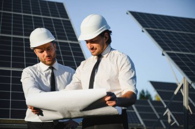 Güneş paneli çiftliği. İki Avrupalı mühendis güneş panellerini inceliyor. Güneş paneli çiftliğindeki işçiler.
