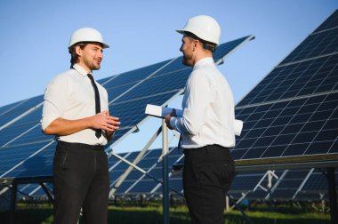 Güneş enerjisi bataryalarının yanındaki işadamı ve işçi.