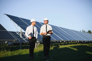 Portrait of engineers standing outside near solar panels. clipart