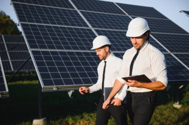 Güneş enerjisi bataryalarının yanındaki işadamı ve işçi.