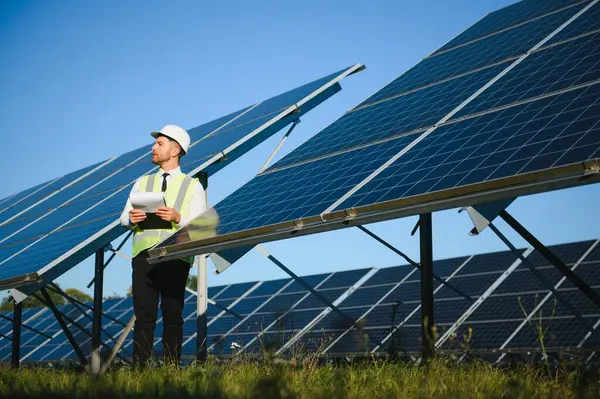 Solar power plant. Man standing near solar panels. Renewable energy.