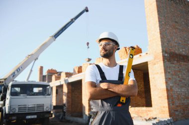 Üniformalı inşaat işçisi ve güvenlik ekipmanı inşaatında çalışıyor.