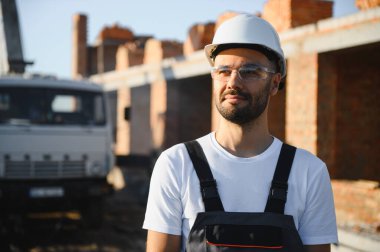 İş yerinde çelik yelek ve şapka takan inşaat işçisinin portresi. İnşaat ve ev tadilatı.