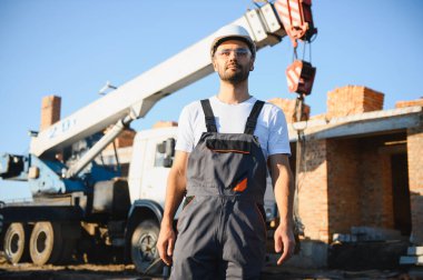 Construction worker in uniform and safety equipment have job on building. Industrial theme.