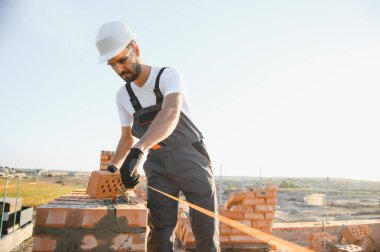 Üniformalı inşaat işçisi ve güvenlik ekipmanı inşaatında çalışıyor.